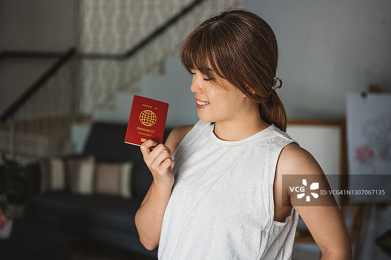 亚洲女人手持新冠免疫护照和行李袋准备旅行图片素材