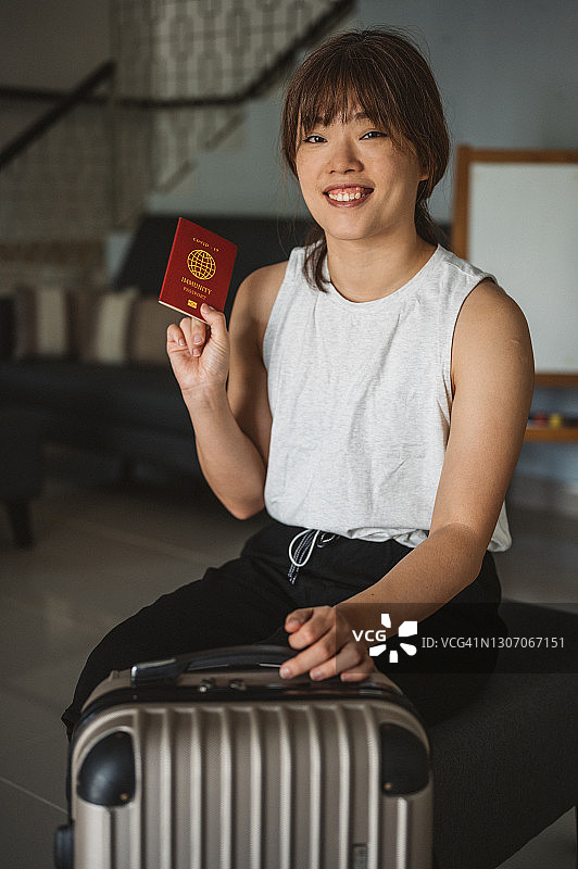 亚洲女人手持新冠免疫护照和行李袋准备旅行图片素材
