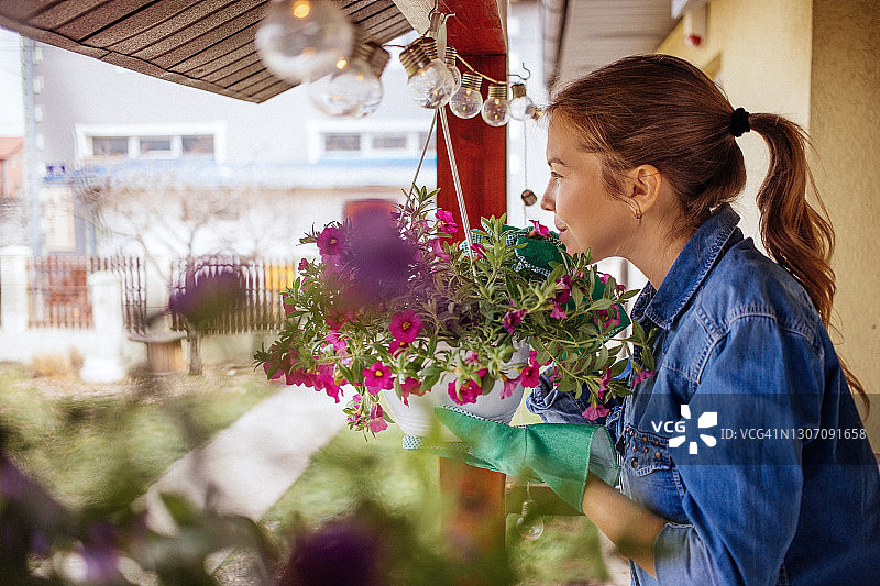 年轻女子在她家门廊整理植物图片素材