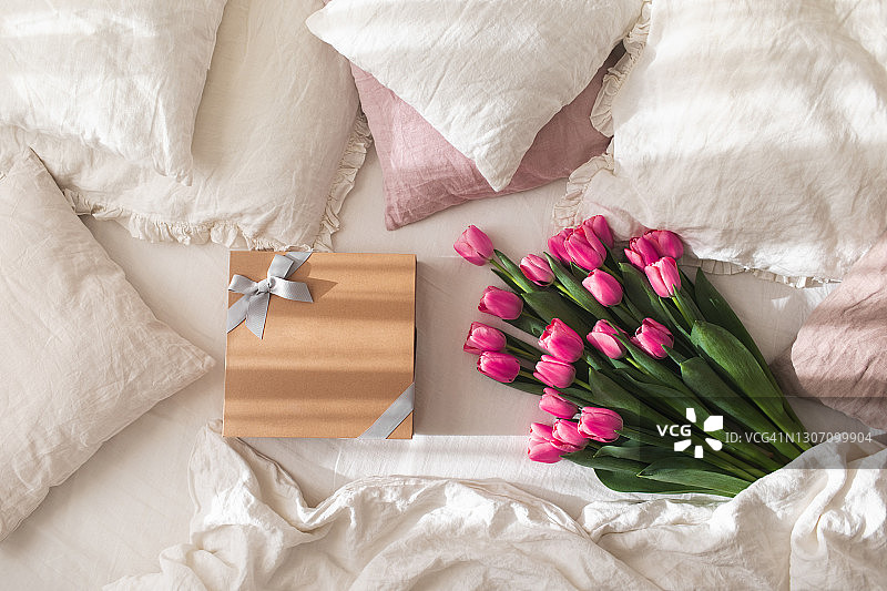 白色亚麻床上放着一束郁金香的礼品盒图片素材