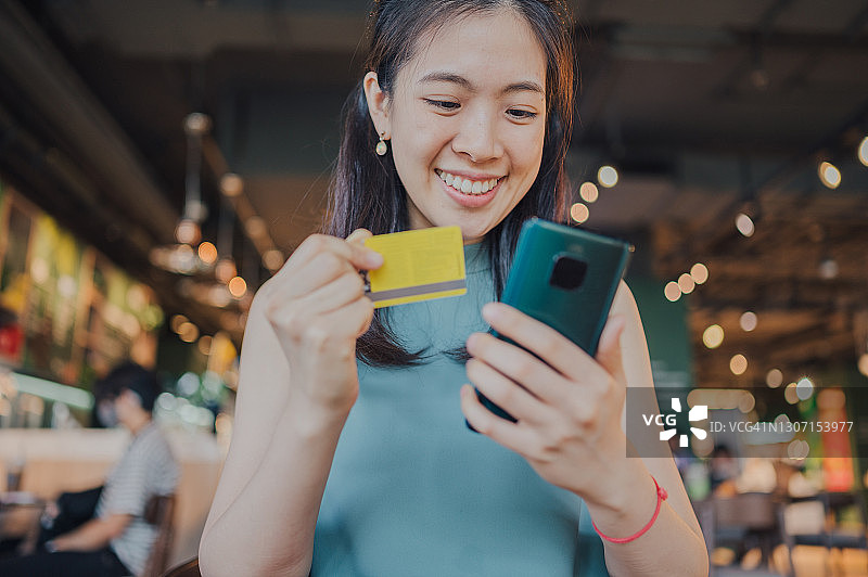 年轻亚洲女性在联合办公空间使用笔记本电脑和信用卡进行网上银行理财图片素材