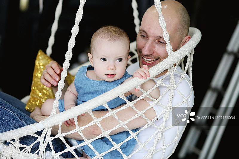 可爱的小女孩和她的父亲在后院的吊床上玩耍和荡秋千图片素材