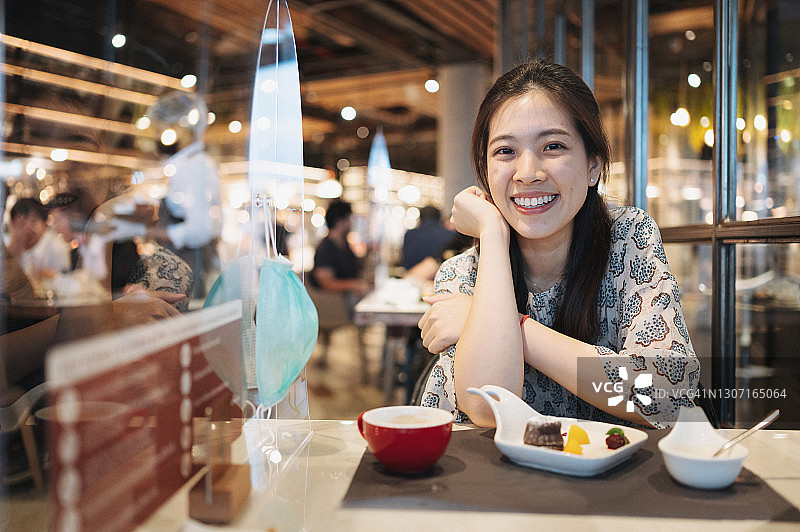 快乐的亚洲人在具有新常态概念的甜点咖啡馆享受，PPE塑料保护，新冠疫情社交疏离概念图片素材