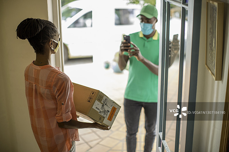快递员拍摄女性收件人手中的包裹图片素材