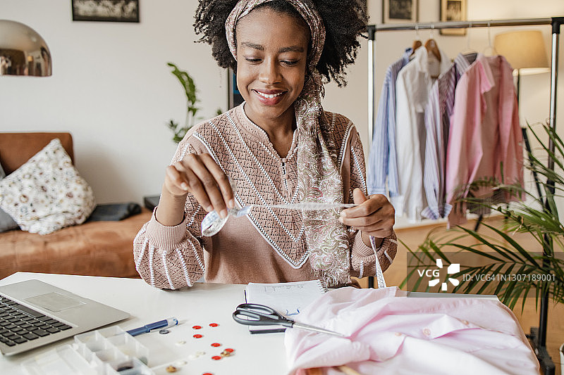 年轻女裁缝在她的家庭工作室工作图片素材