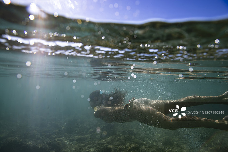 穿着比基尼的健康女性在浅而清澈的海洋中游泳，天空图片素材