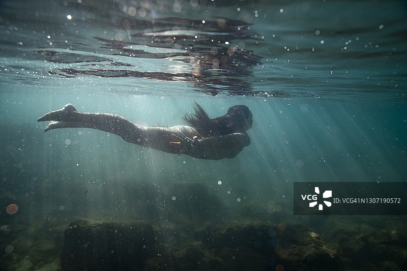 女人在阳光照射的浅水中游走图片素材