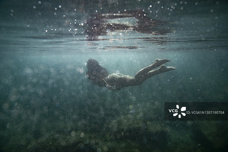 在清澈的蓝色海洋中与气泡一起游泳的女人图片素材