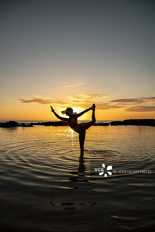 夕阳下浅水中跳舞姿势的女人图片素材