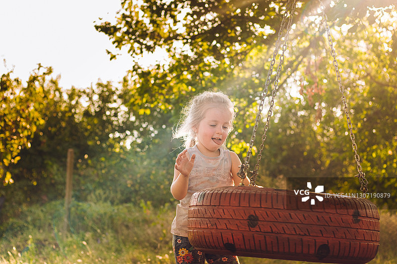 快乐小女孩在夏天玩轮胎秋千图片素材