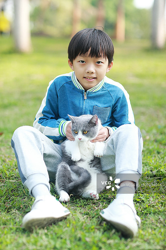可爱的年轻男孩依偎着他的小猫。图片素材
