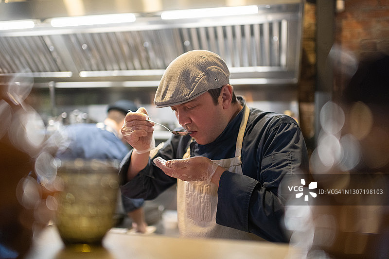 男厨师在咖啡馆厨房里品尝菜肴图片素材
