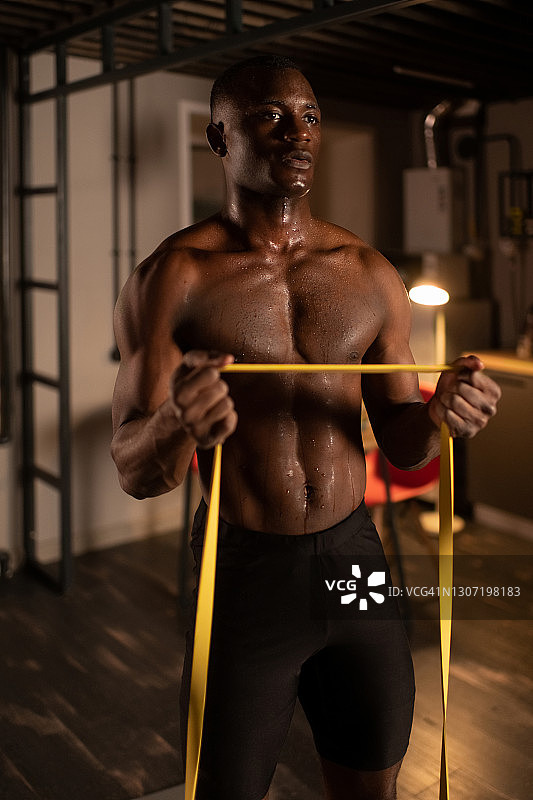正在用弹力带训练的黑人男性运动员图片素材