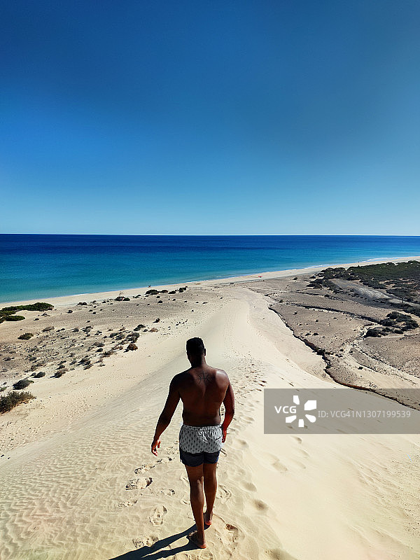 黑人男子走在富埃特文图拉岛索塔文托海滩的沙丘上图片素材