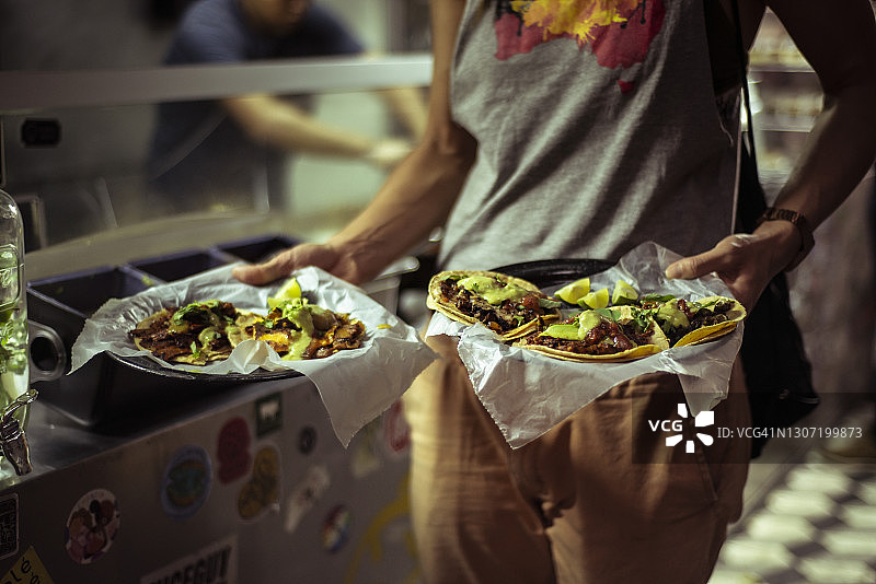 游客手拿的健康墨西哥街头塔可卷饼图片素材