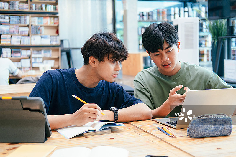 年轻学生在校园里帮助朋友赶上学习进度图片素材