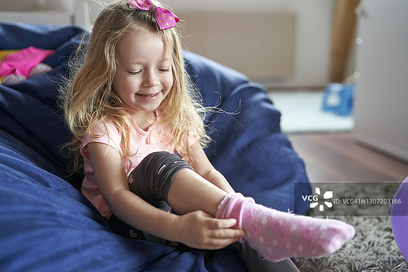 快乐的小女孩坐在豆袋上穿粉色袜子图片素材