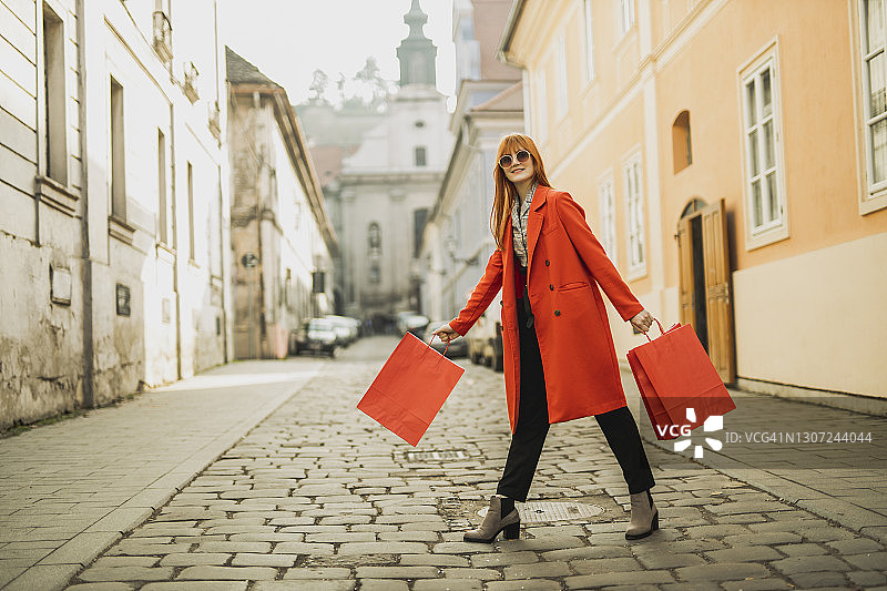 红发女孩在城市里拎着购物袋图片素材
