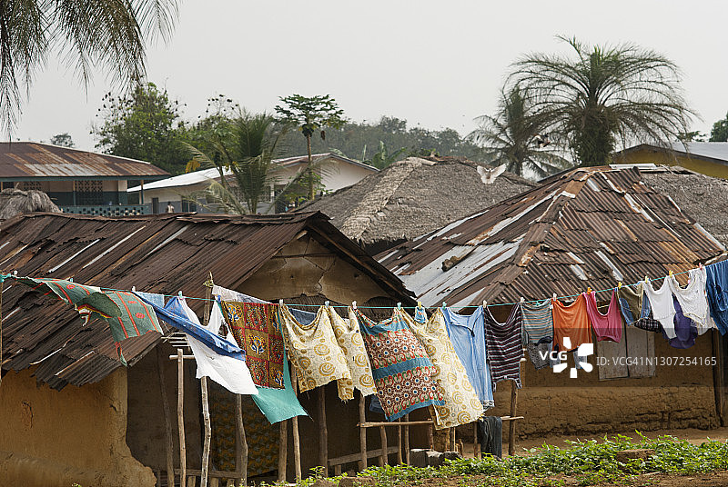 利比里亚偏远村庄的传统泥屋，晾衣绳上挂着洗好的衣物图片素材
