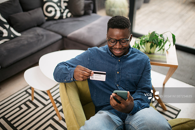 快乐的年轻非裔美国男人在家购物图片素材