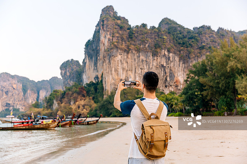背着背包的旅客在泰国甲米海滩用手机拍摄山脉图片素材