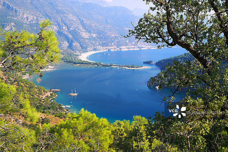 从山上看到的土耳其费特希耶附近厄吕代尼兹泻湖的蓝色水面，地中海山地树木繁茂的海岸，晴朗的天空图片素材