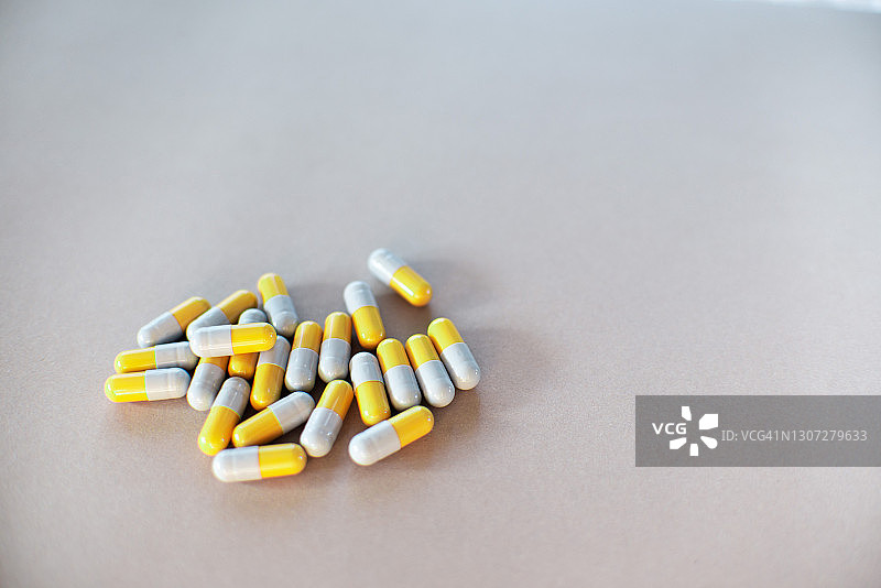 灰色背景上的黄色和灰色胶囊，健康医疗概念图片素材
