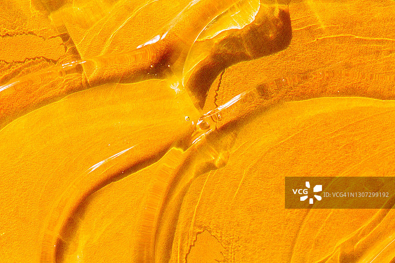 化妆品背景由鲜橙色背景上的化妆品凝胶涂片组成。年度潮流身体护理程序概念图片素材