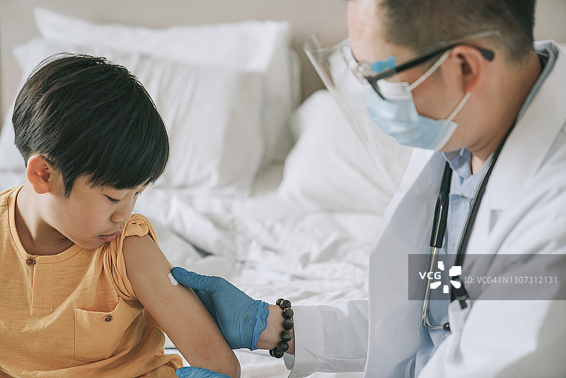 华人医生给注射后的男孩手臂贴上创可贴图片素材