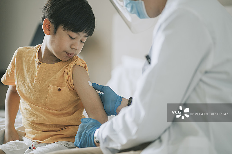 华人医生给注射后的男孩手臂贴上创可贴图片素材