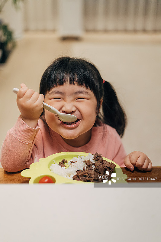 小女孩在餐桌旁吃烤肉拌饭图片素材