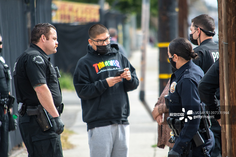 一群洛杉矶警察局的警官和主管在帕提尼附近的住宅区对一起袭击事件进行调查图片素材