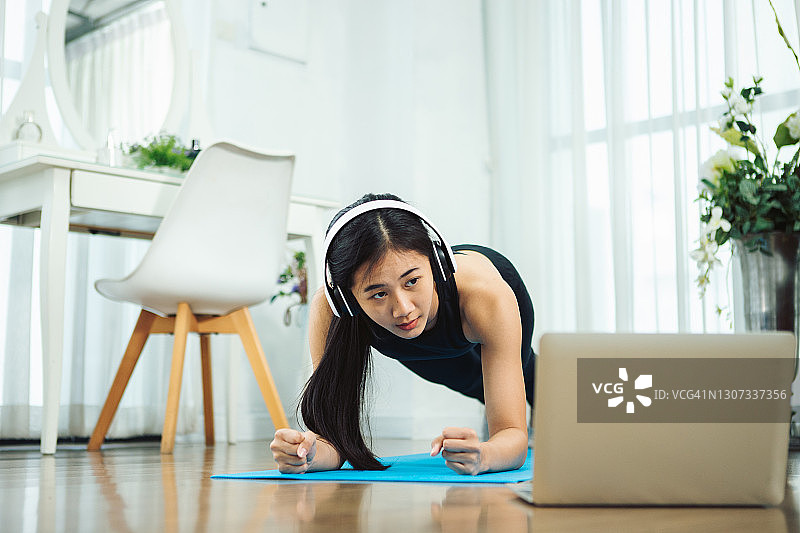 在家对着笔记本电脑伸腿锻炼的女人图片素材
