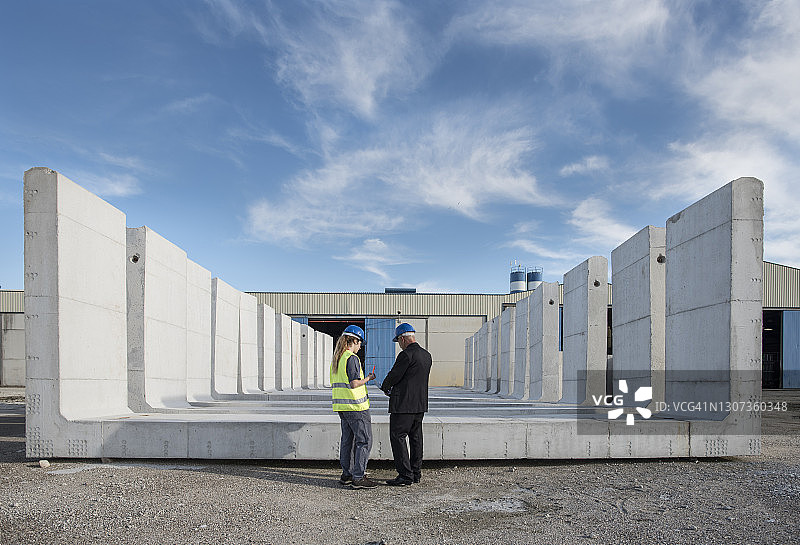 在西班牙科尔多瓦，女工和施工经理在混凝土建筑附近友好交谈图片素材