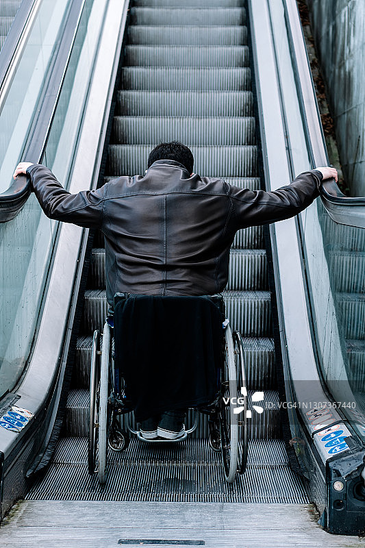 坐轮椅的残疾男子乘坐自动扶梯图片素材