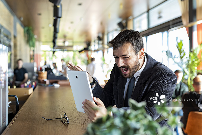 在咖啡馆用平板电脑进行视频会议的自信年轻商人图片素材