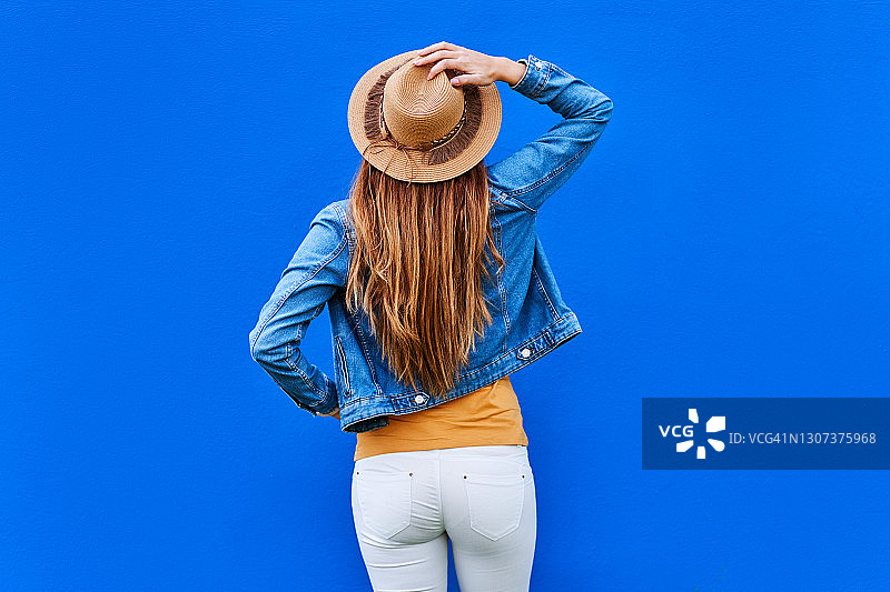 戴着时髦帽子的时尚年轻女人（蓝色背景）图片素材