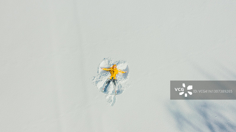 航拍：身穿黄色雨衣的年轻男子在雪地上玩耍图片素材