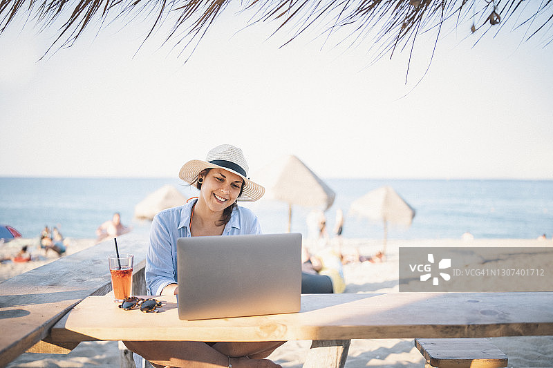 年轻女性度假时使用笔记本电脑的肖像图片素材