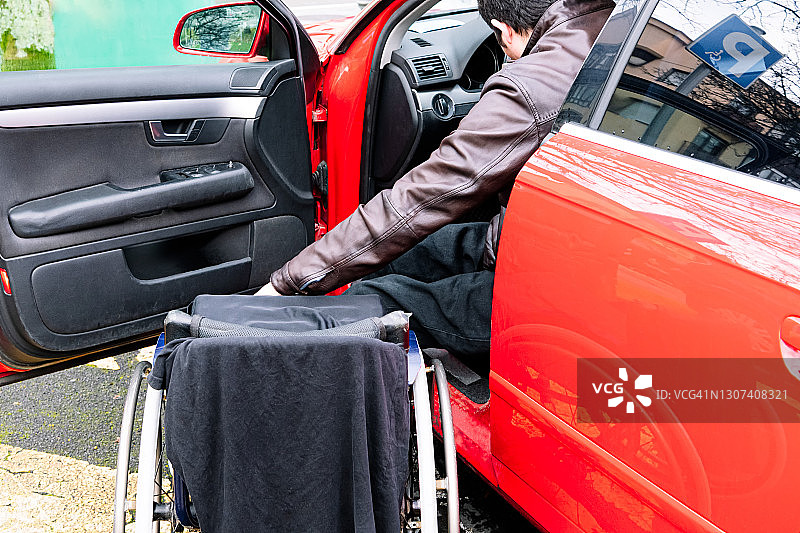 残疾男子将双腿移出汽车，并将垫子放在轮椅上准备坐下图片素材