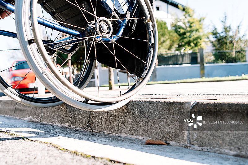 坐轮椅的男人在不方便轮椅通行的路边下路细节图片素材