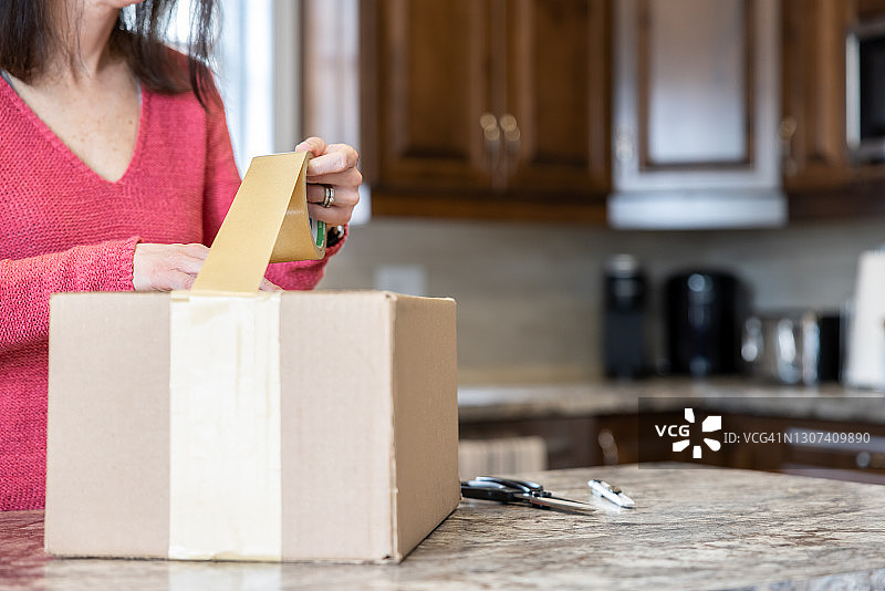 女人在包裹上贴胶带，准备发货和退货图片素材