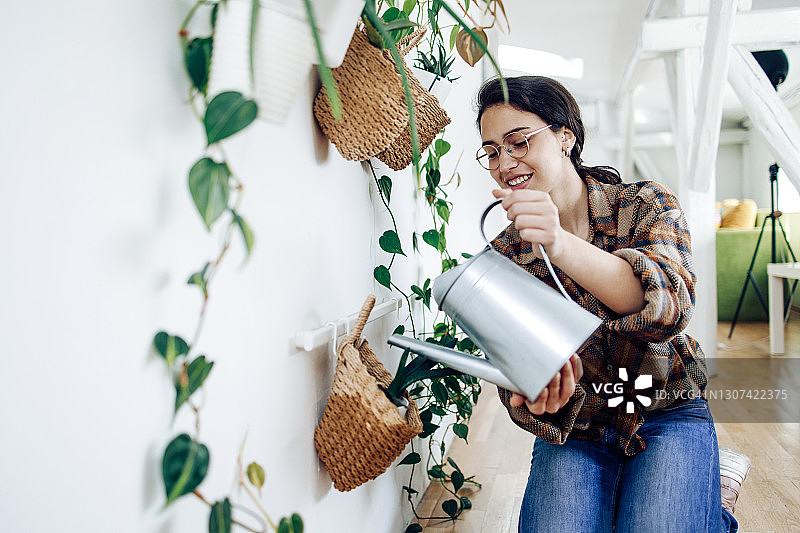 美丽的年轻女子在公寓里照料植物图片素材