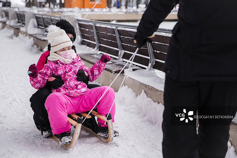 女孩们戴着防护面具被拉上雪橇图片素材