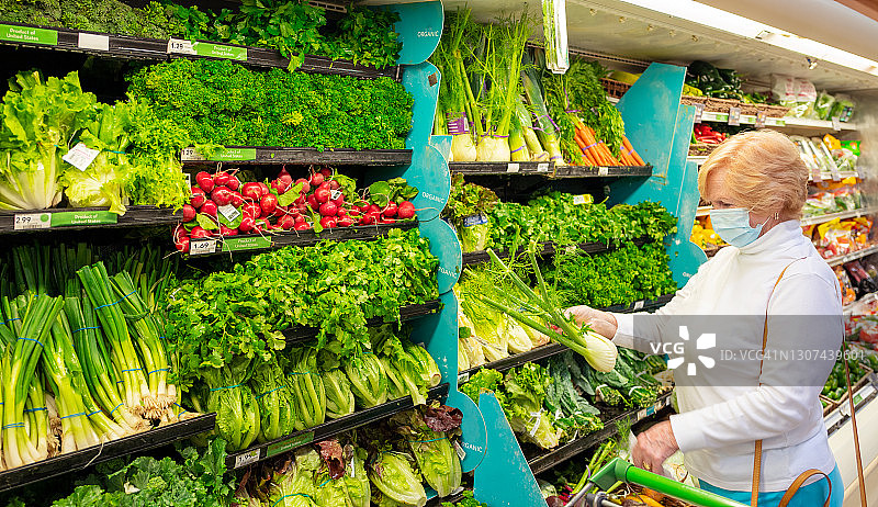 妇女在超市购买有机农产品，戴着口罩图片素材