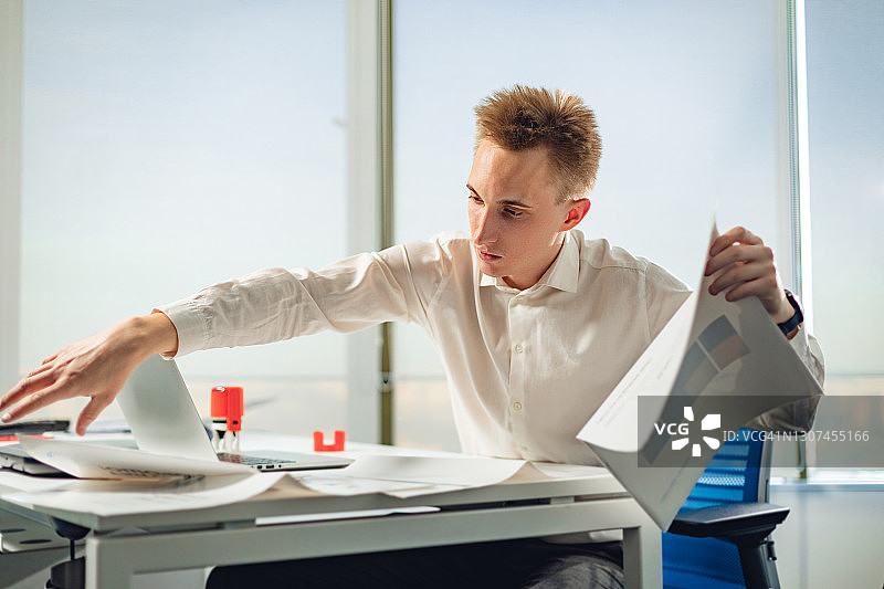 室内年轻商务男士人像：商务人士使用笔记本电脑处理项目图片素材