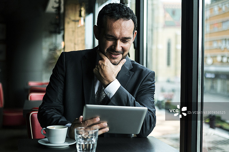 商人喝咖啡，手持平板电脑图片素材