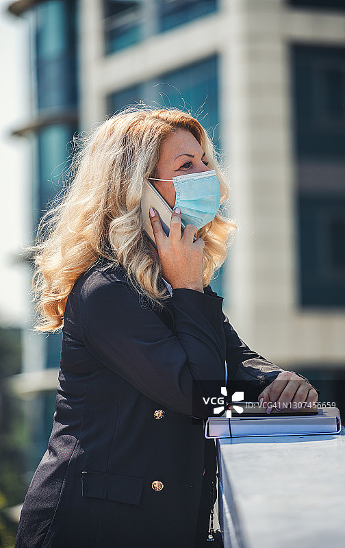 新冠疫情期间在户外戴防护口罩的女商人肖像图片素材