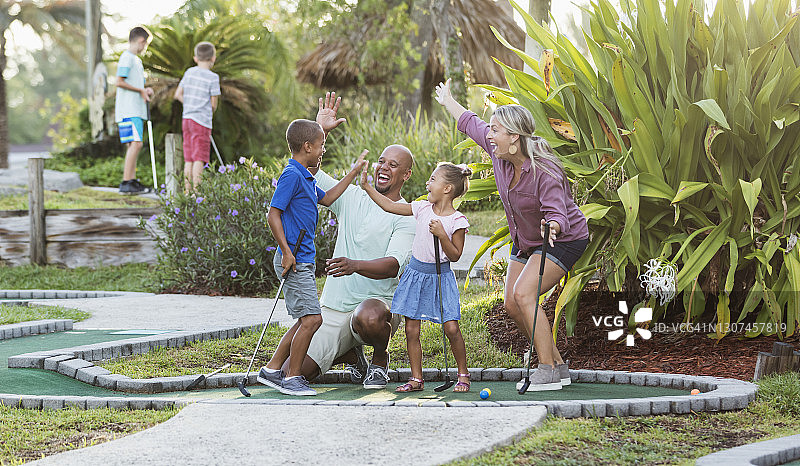 跨种族家庭，两个孩子在玩迷你高尔夫图片素材