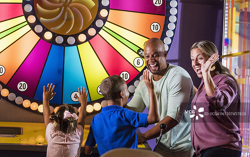 跨种族家庭：两个孩子赢得街机游戏图片素材